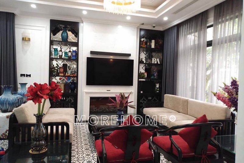 . Phòng khách được trang bị nội thất theo phong cách truyền thống bằng bộ sofa gỗ Việt cao cấp, đệm trắng và đệm đỏ kết hợp lại tạo nên một vẻ đẹp ấm áp cho căn phòng.